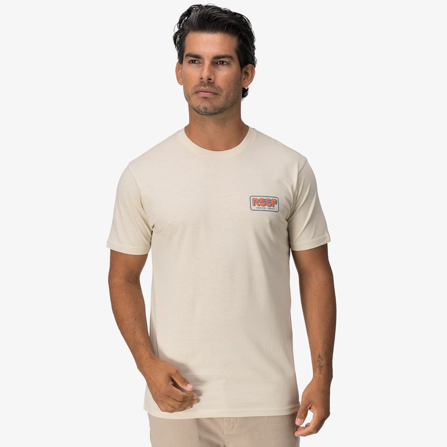 Man wearing a beige Quinn Tee, front view, casual fit, surf-inspired comfort apparel for men, beach lifestyle.