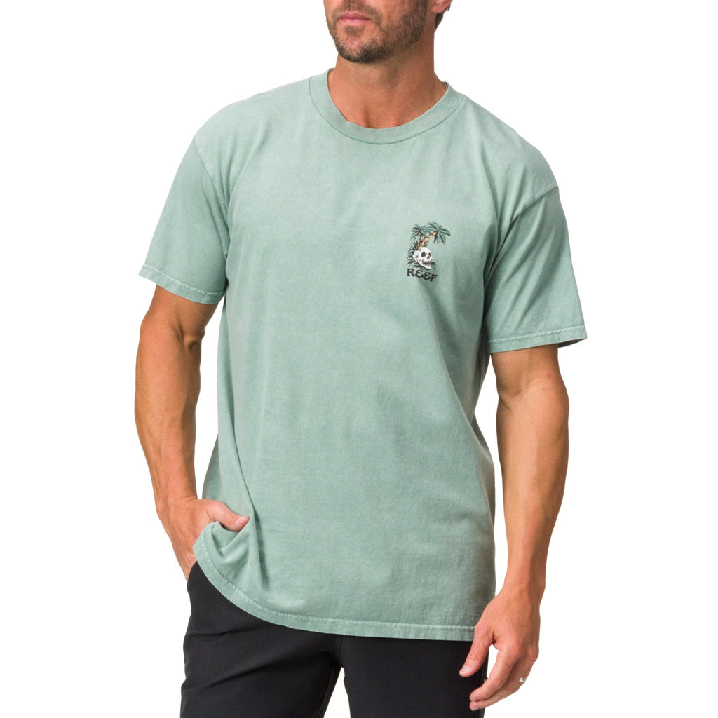 Front view of a man wearing a green Akin Tee with a small palm tree graphic, surf-inspired casual apparel for men.