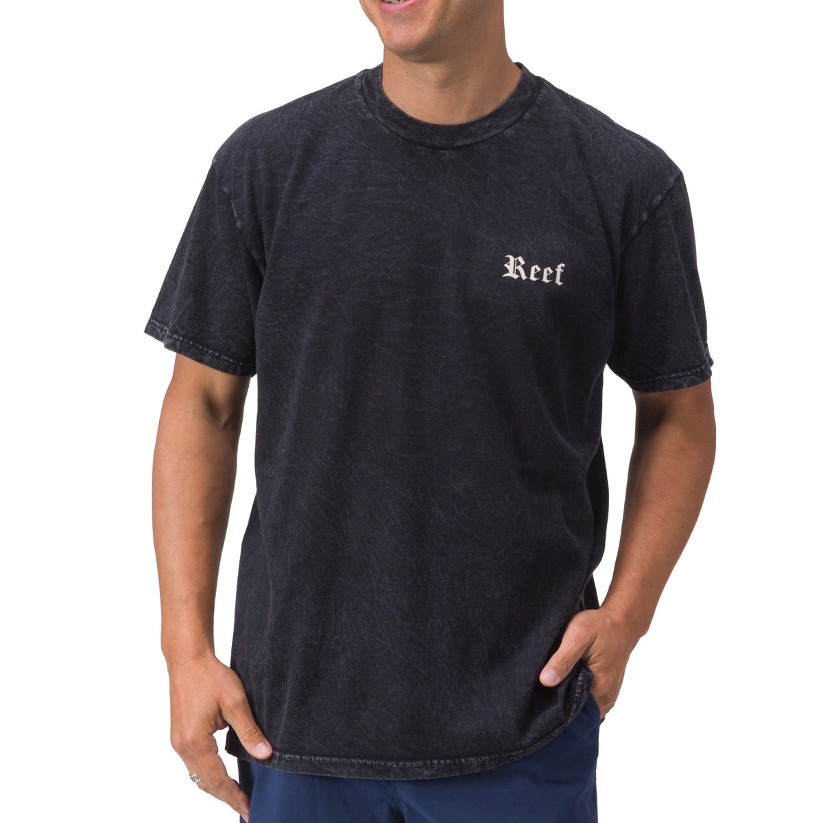 Front view of a man wearing a black Pray Tee with Reef logo, relaxed fit, beach-inspired comfort apparel for men.