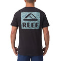 Rear view of men's Shells Tee in black with large REEF logo on blue patterned background, beach-inspired comfort apparel.