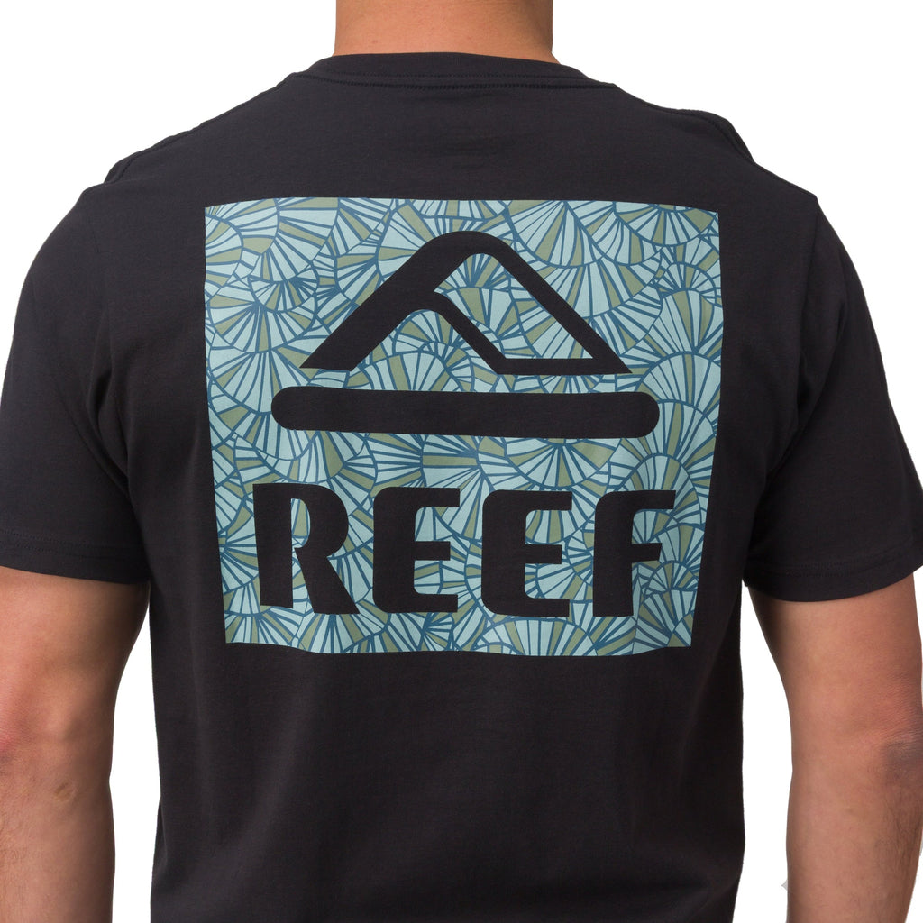 Back view of man wearing Shells Tee in black with blue shell patterned REEF logo, surf-inspired comfortable men’s apparel.
