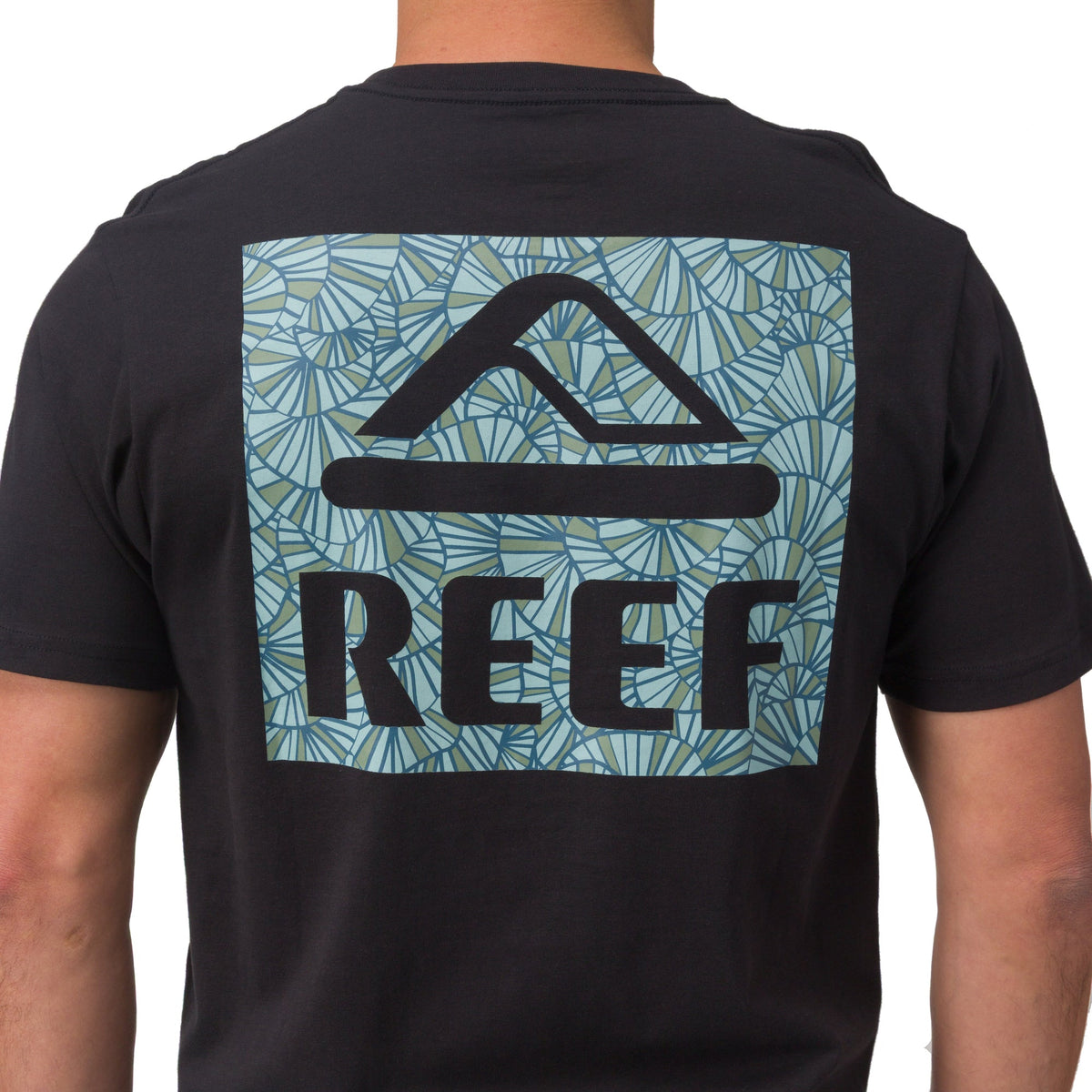 Back view of man wearing Shells Tee in black with blue shell patterned REEF logo, surf-inspired comfortable men’s apparel.