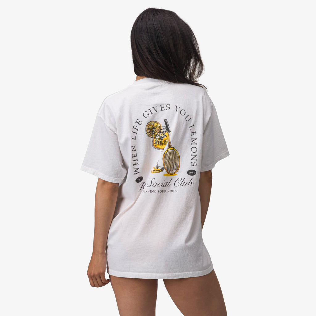 Woman wearing the Social Boyfriend Crew tee facing away, showing back graphic with lemons and tennis racquet.