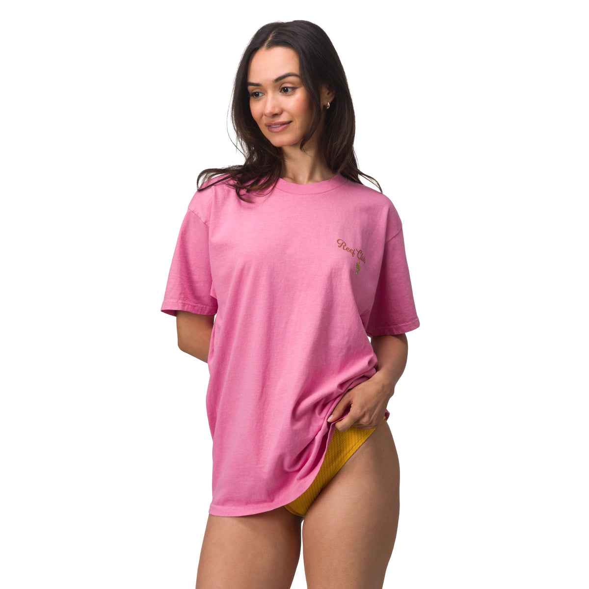 Woman wearing pink oversized t-shirt with surf-inspired design, standing with relaxed pose, showcasing summer comfort apparel.