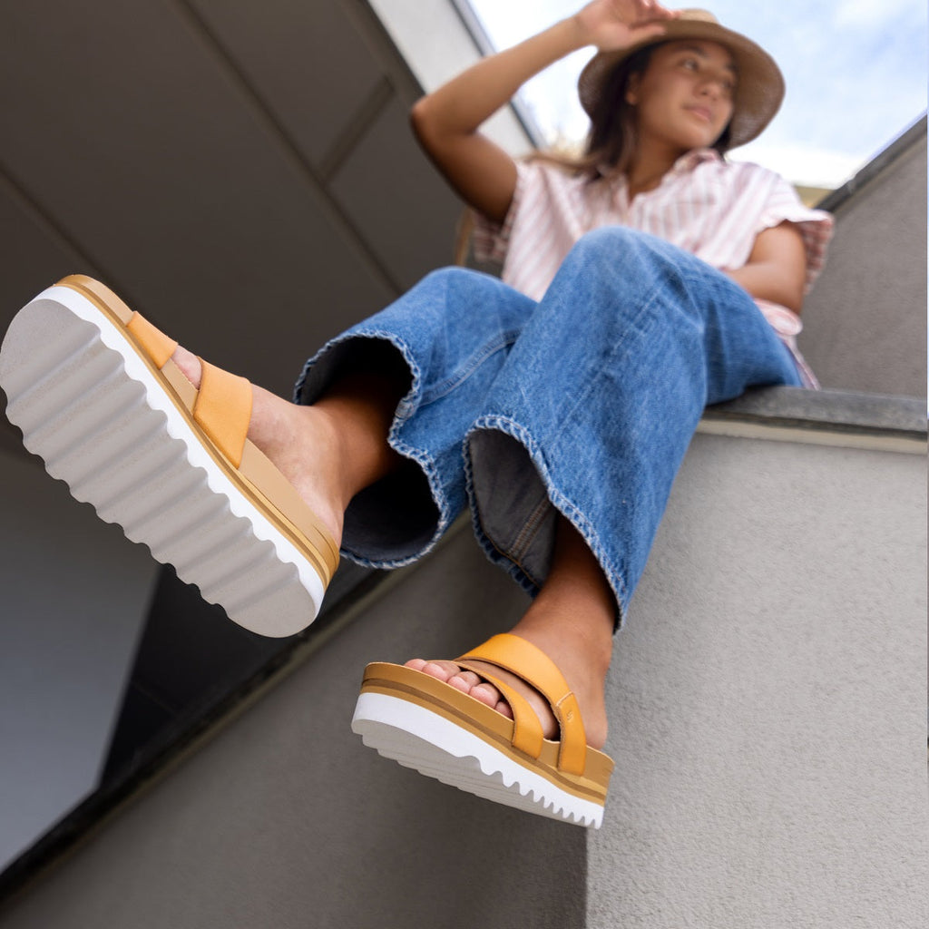 woman sitting on ledge in reef platform sandals