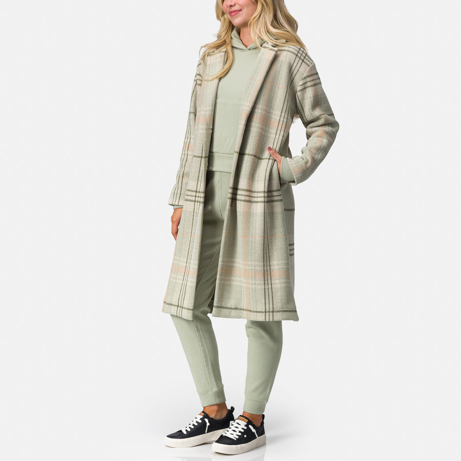 Woman wearing Beverly Knit Trench in desert sage plaid facing left, showcasing a surf-inspired comfortable casual look.
