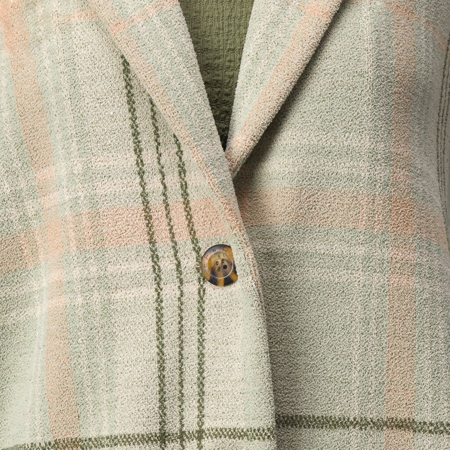 Close-up of the olive green and beige plaid Beverly Knit Trench showing textured fabric and button detail.