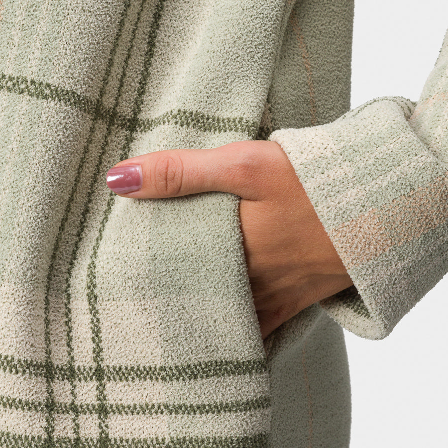Close-up of a woman's hand in the pocket of the Beverly Knit Trench in desert sage plaid fabric, showing texture and stitching.