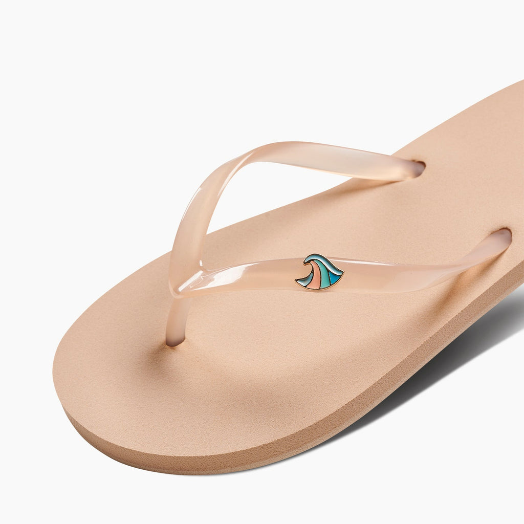 Kids Charming flip flop facing right, close-up of footbed and transparent thong strap with small wave logo detail