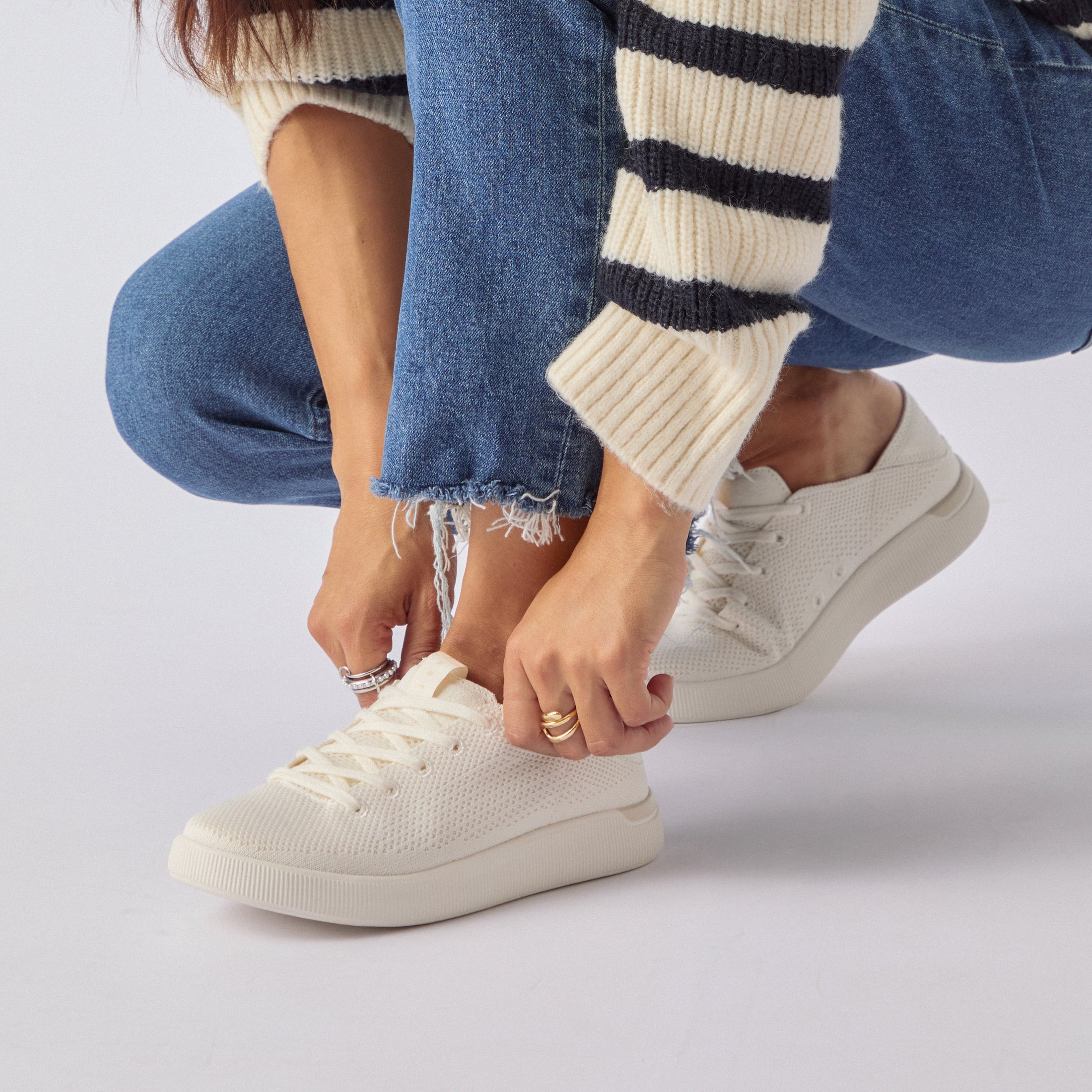 Woman wearing Reef Neptune sneakers in cream knit, right shoe facing left, close-up on lacing and upper toe area.