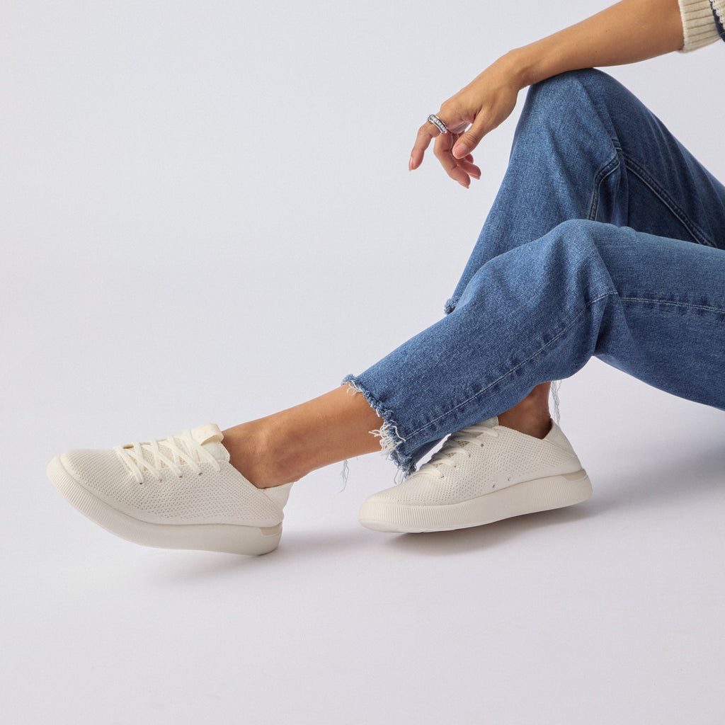Side view of Reef Neptune cream knit sneaker on woman's feet, highlighting lightweight, cushioned, beach-inspired comfort.