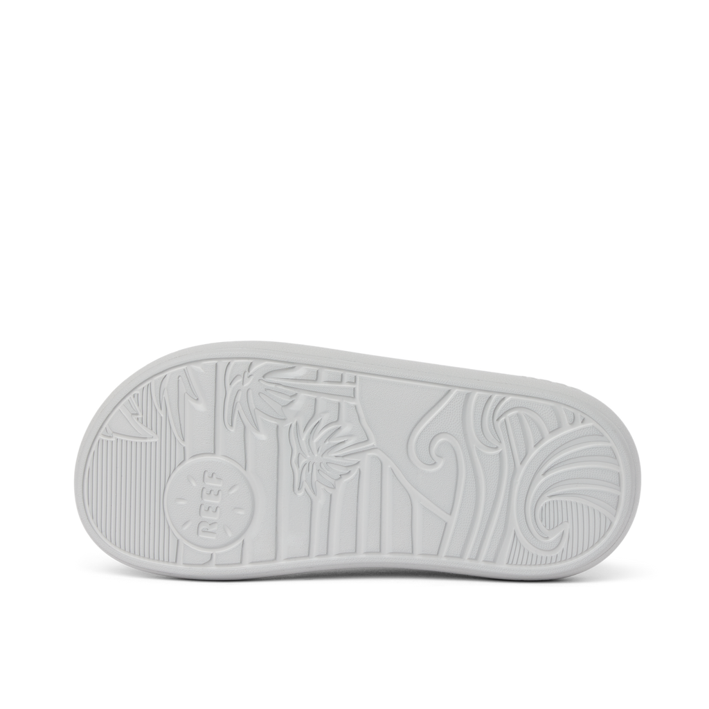 Kids Rio Slide outsole facing up showing textured beach-inspired sole with palm tree and wave patterns in light grey