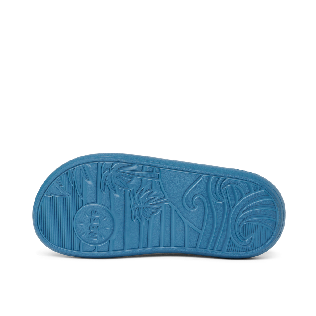 Kids Rio Slide showing the bottom sole facing up with surf-inspired wave and palm tree tread pattern in navy blue rubber