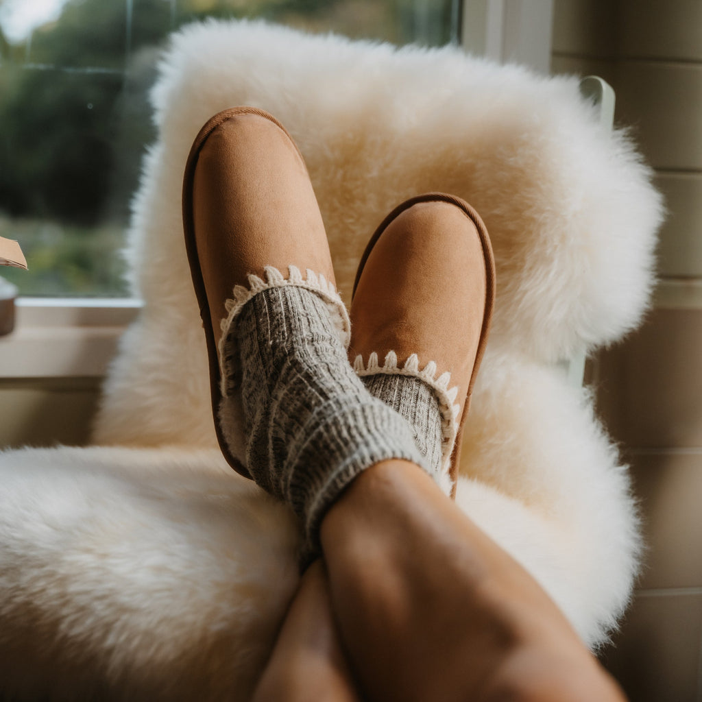 Iryss tan slip-on footwear facing forward, close-up of cushioned top with anatomical arch support, worn with cozy socks.