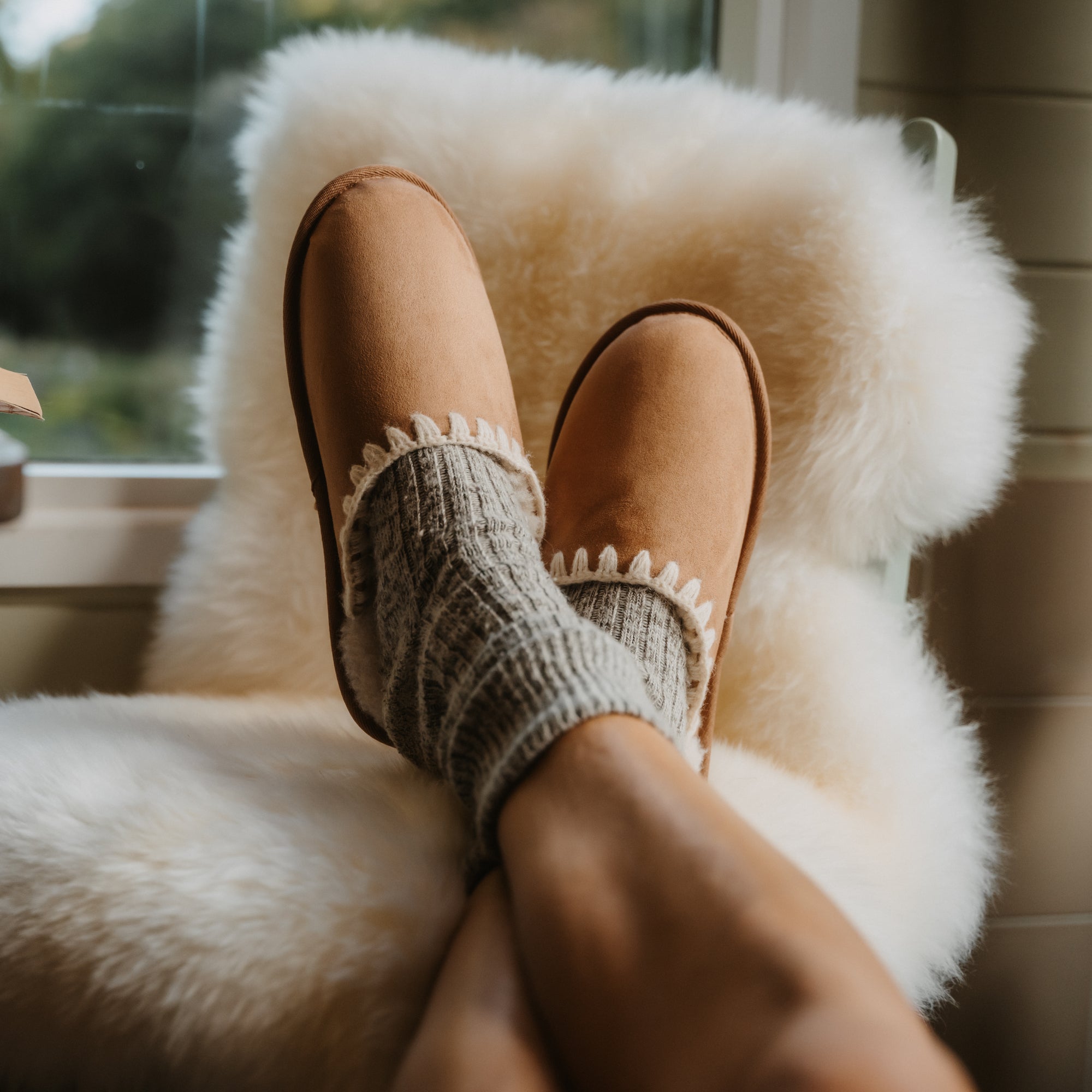 Iryss tan slip-on footwear facing forward, close-up of cushioned top with anatomical arch support, worn with cozy socks.