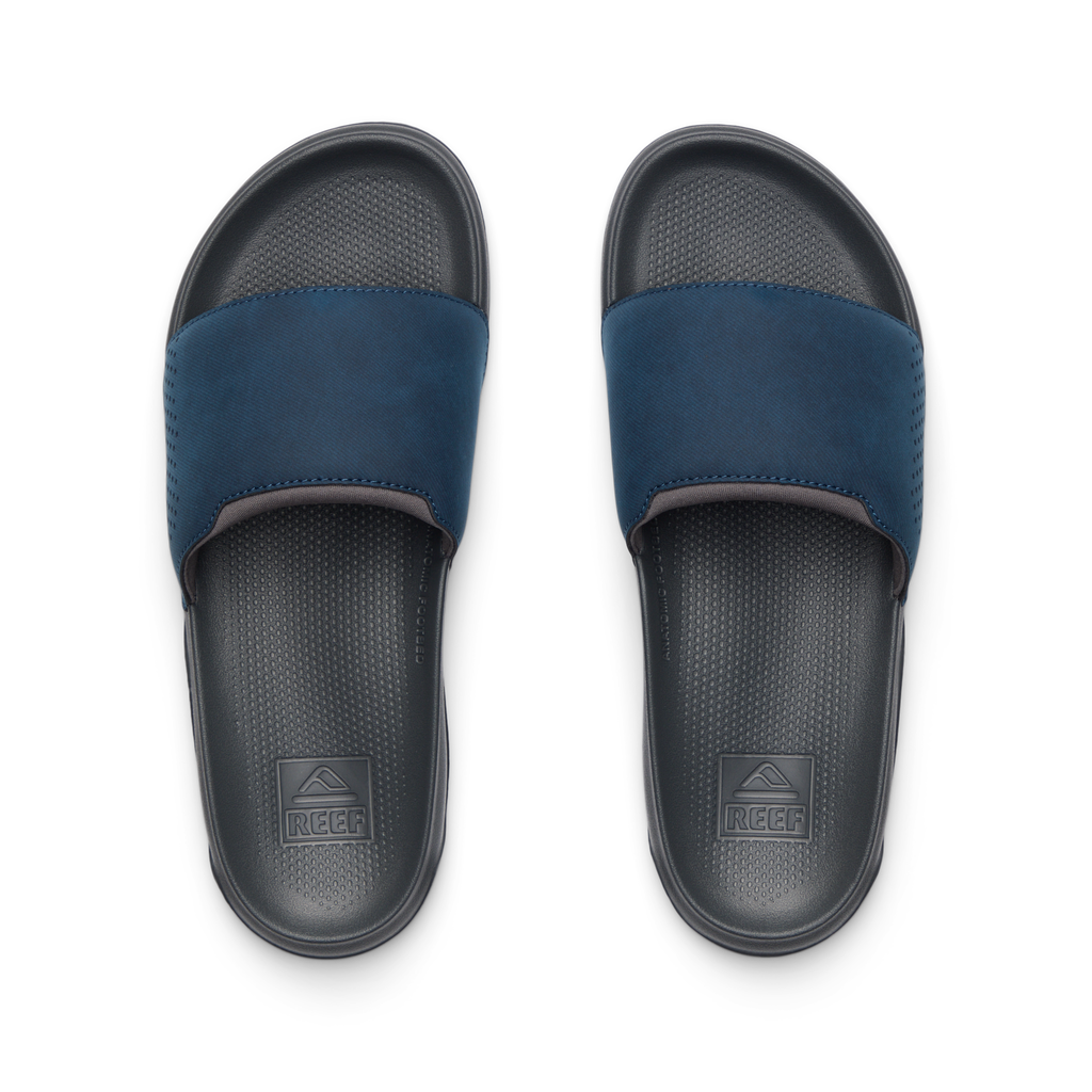 Tailslide men's slides facing upward, navy blue strap with textured grey footbed, water-friendly comfort and arch support.