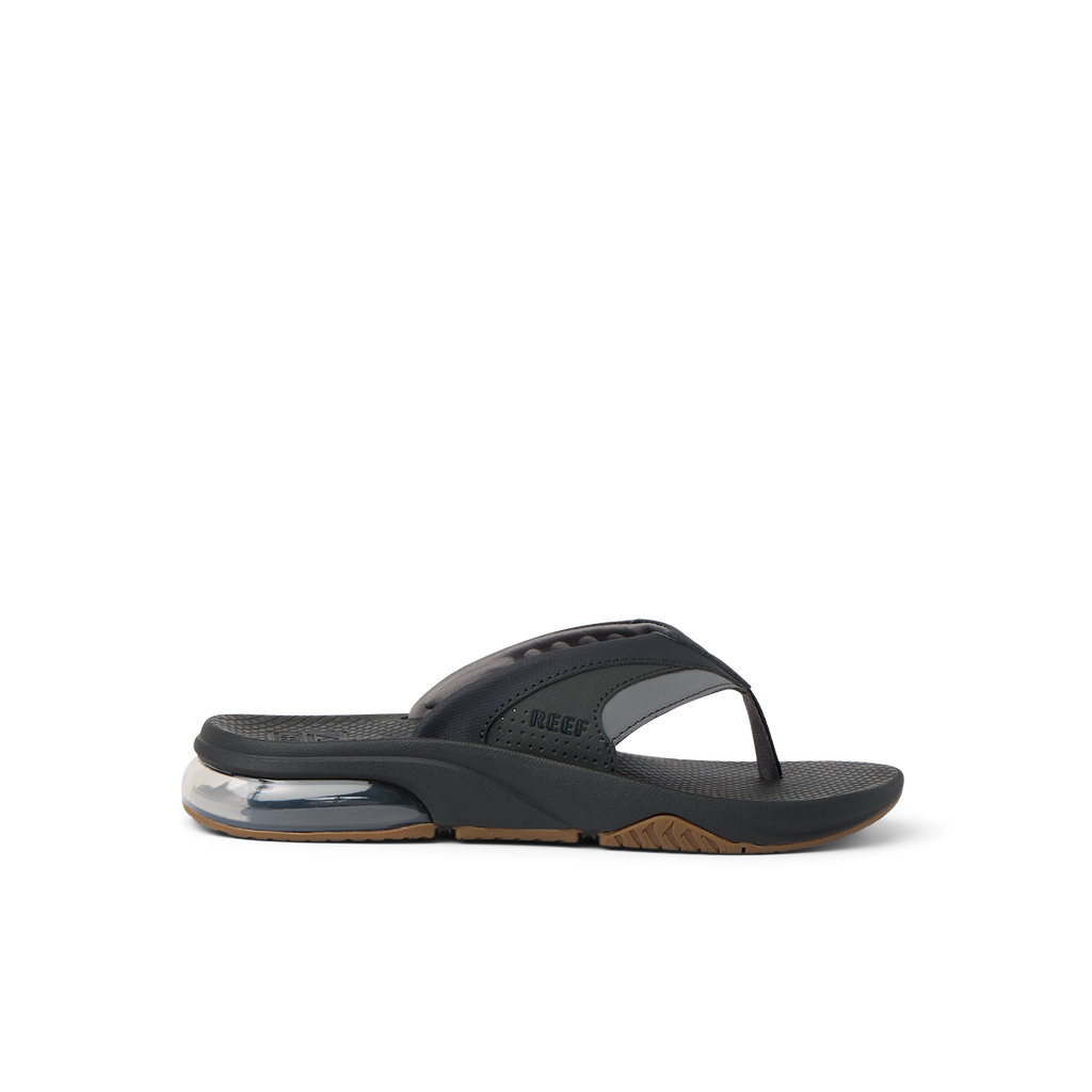 Fanning + men's black and gum flip flop facing left, close-up on the side showing cushioning and arch support.