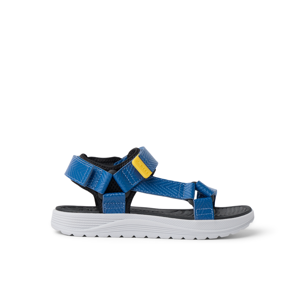 Kids Shoremazing sandal for boys facing right, showing side view with blue straps and white sole, designed for beach comfort.
