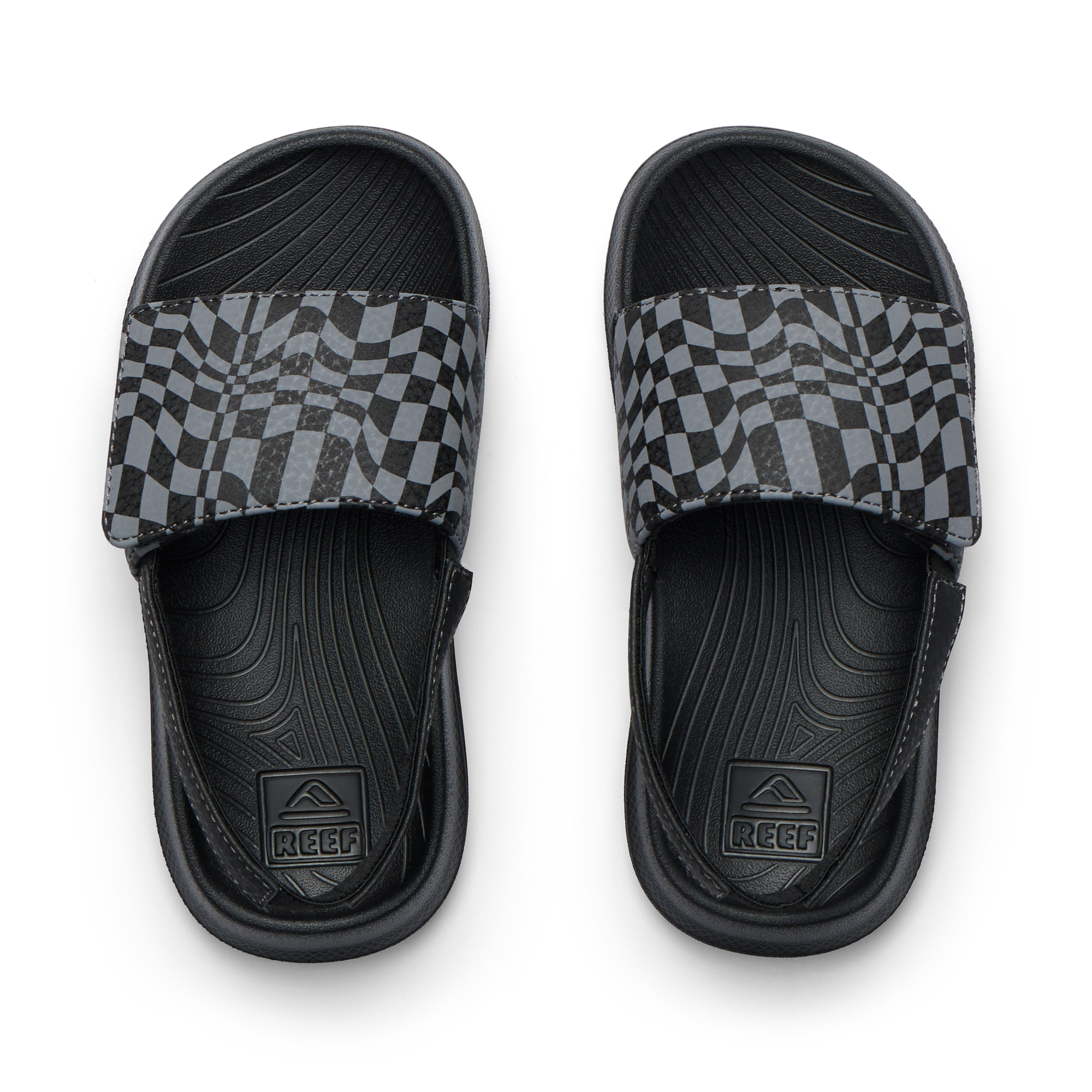 Pair of Little Salty Slide sandals for boys facing up, featuring black checker pattern and anatomical arch support.