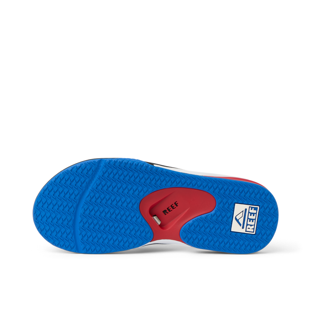 Fanning men's shoe sole facing up, showing blue textured grip and red arch support with REEF branding.