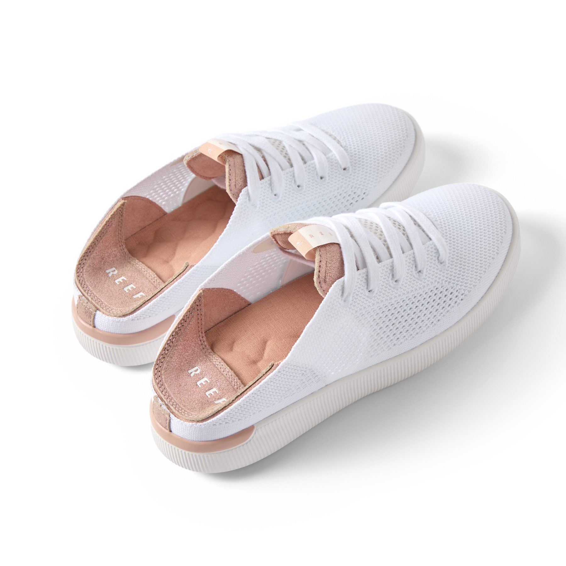 Reef Neptune women's white and rose gold sneakers angled side view showing lightweight knit upper and cushioned heel.