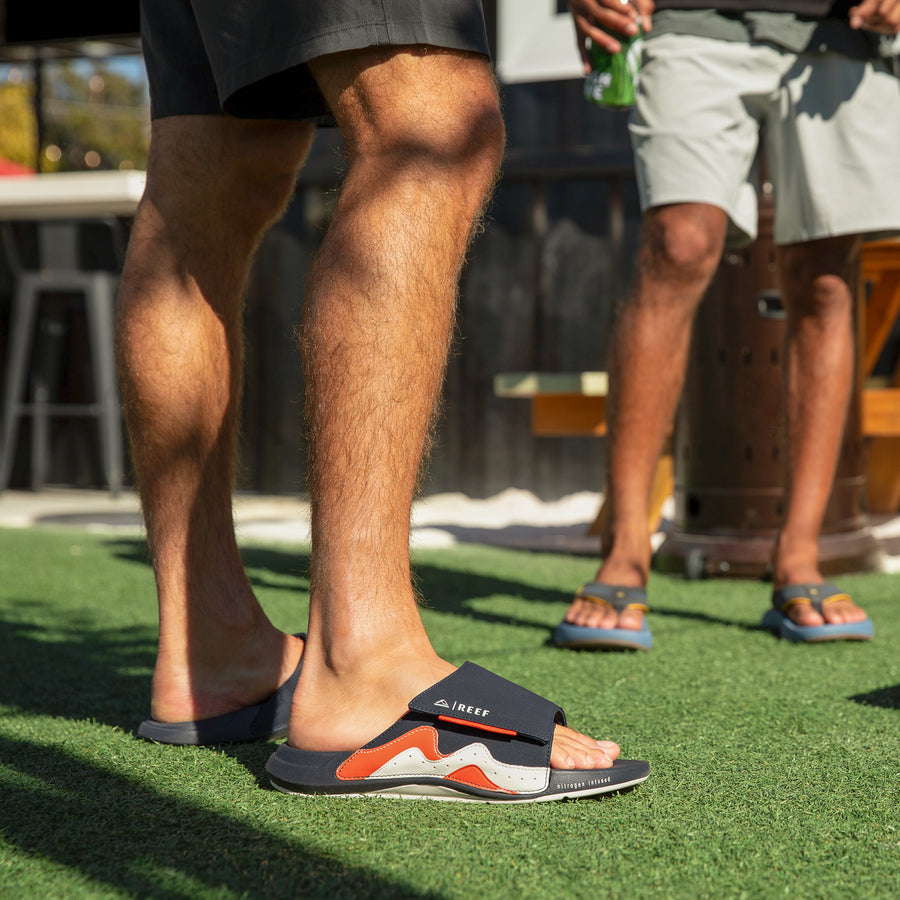 Right-facing Cruiser Slide on adult man's foot showing side and top views with surf-inspired comfort design outdoors.