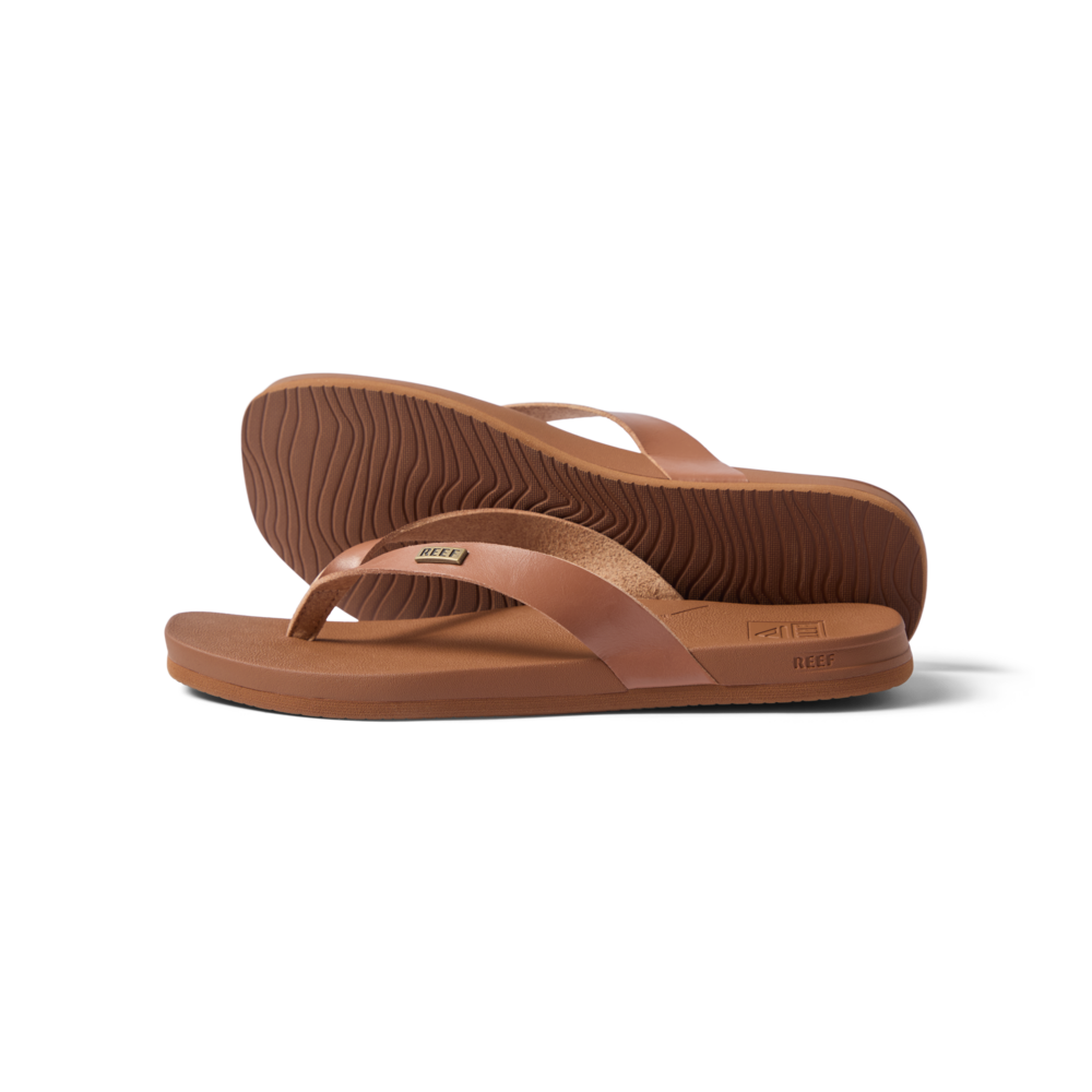 Vista Lune women's tan flip flops facing right, close-up on sole and strap, beach-inspired comfort and arch support sandals.