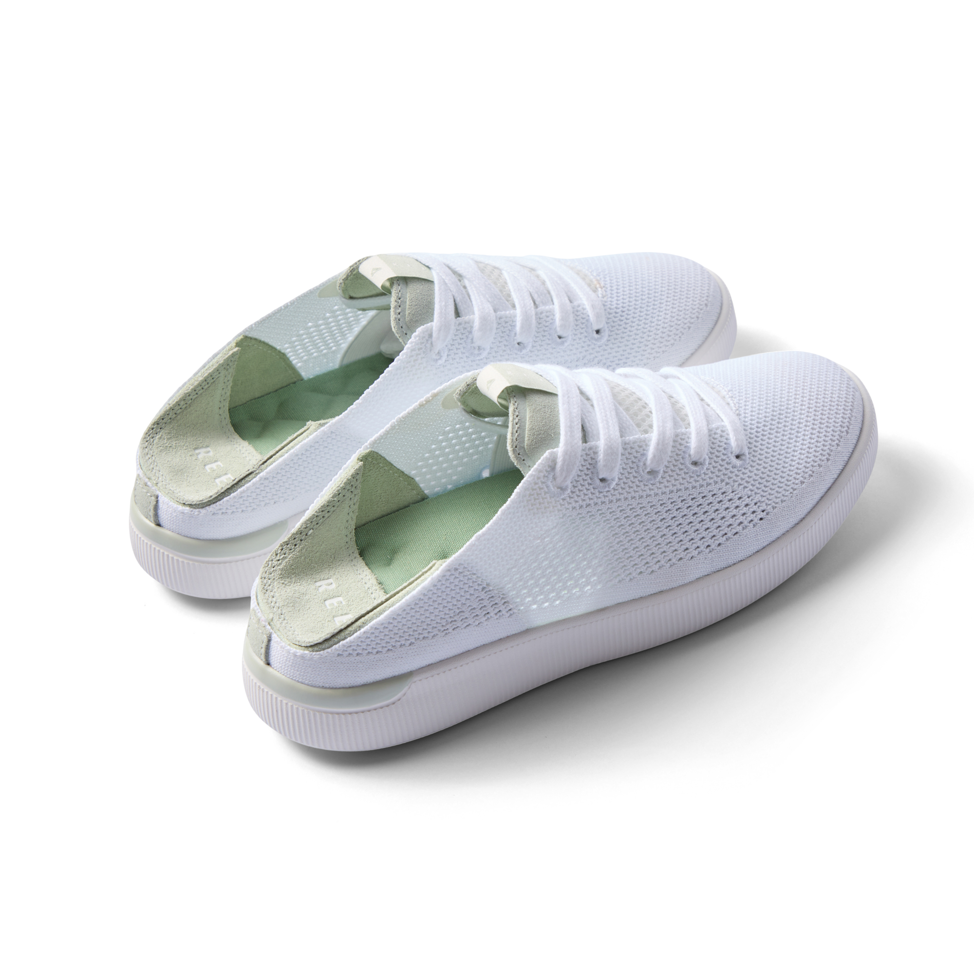 Pair of Reef Neptune shoes facing right, featuring white and dusty sage colors, knit material, and cushioned arch support.