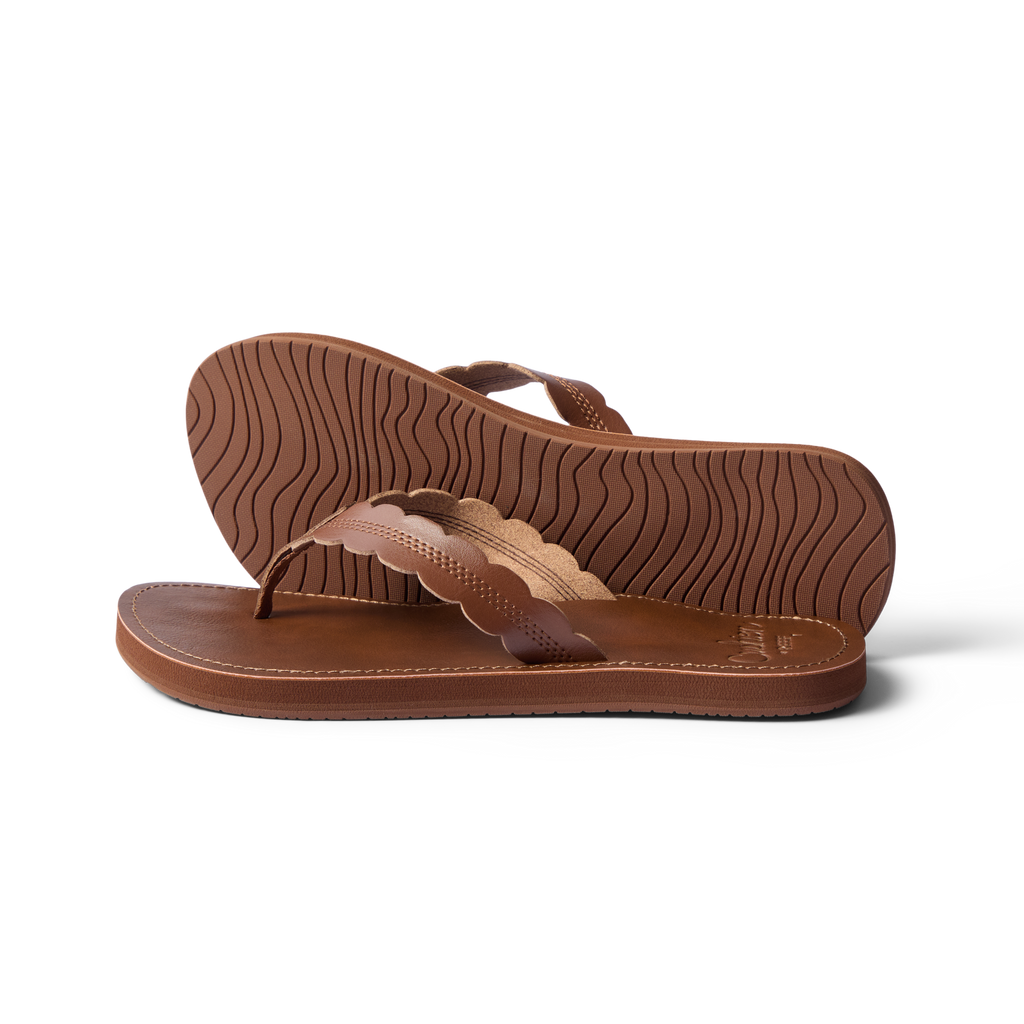 Pair of Reef Cushion Celine sandals in chocolate brown, left facing, showing sole tread and scalloped straps close-up.