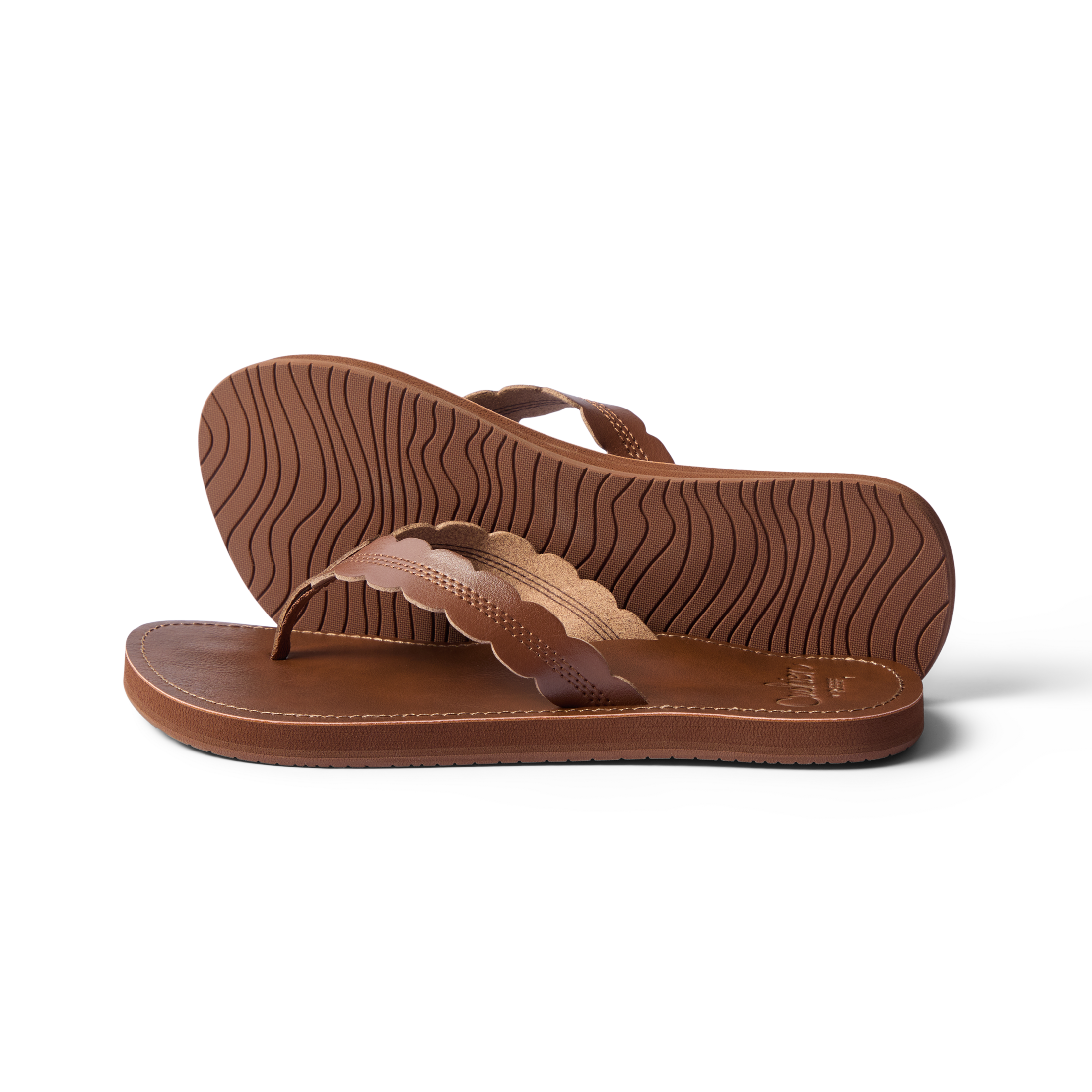 Pair of Reef Cushion Celine sandals in chocolate brown, left facing, showing sole tread and scalloped straps close-up.