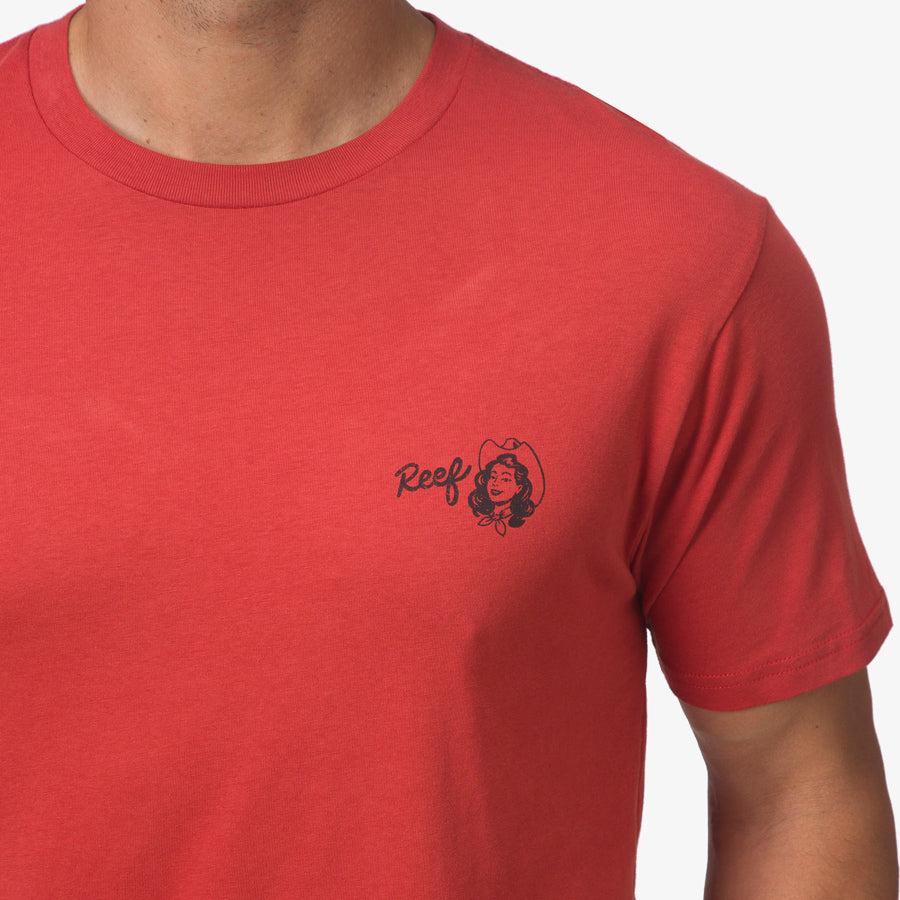 Close-up of the chest area of the red Cowmaid Tee showing the small black Reef logo for men’s beach-inspired apparel.
