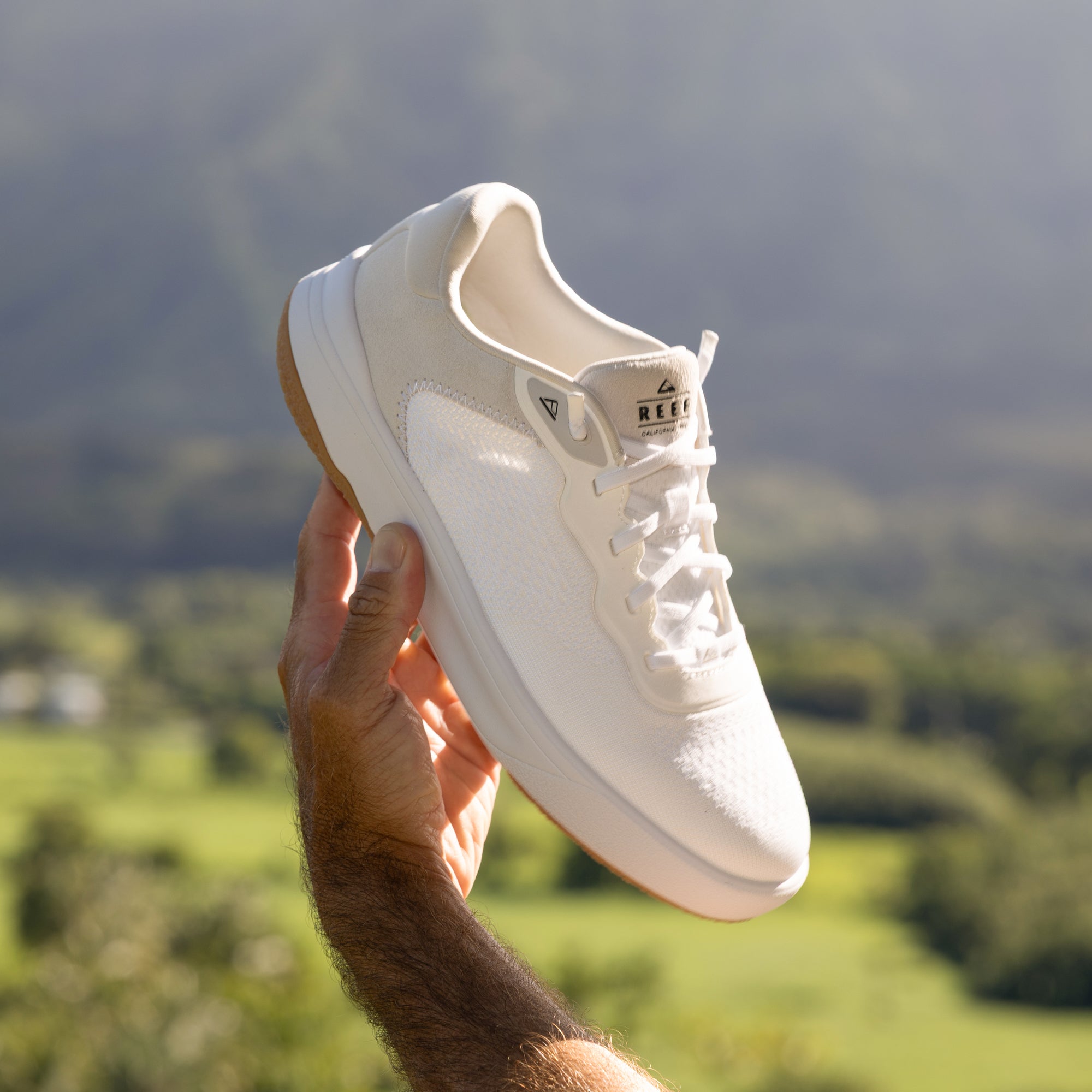 Hand holding Shoreline Del Mar sneaker facing left, showing front and side with comfort-focused design details.