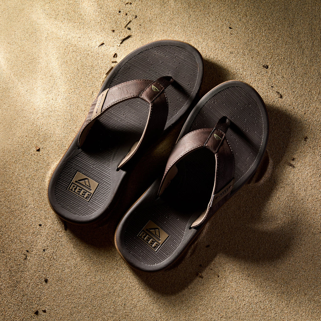 Reef Santa Ana men's sandals in brown facing upward, showcasing cushioned footbed and arch support on sand.