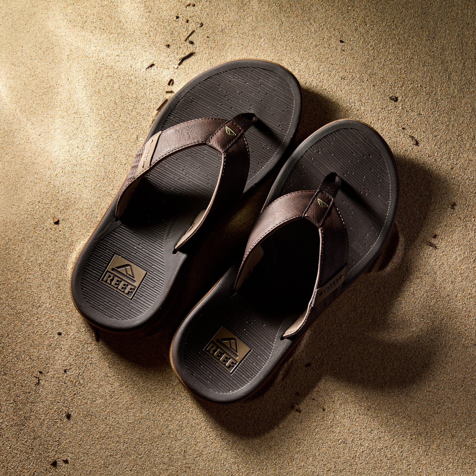 Reef Santa Ana men's sandals in brown facing upward, showcasing cushioned footbed and arch support on sand.