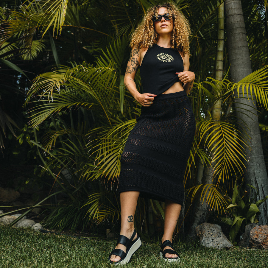 Woman wearing Mika Sweater Skirt and sandals facing forward, styled for beach comfort with a surf-inspired look.