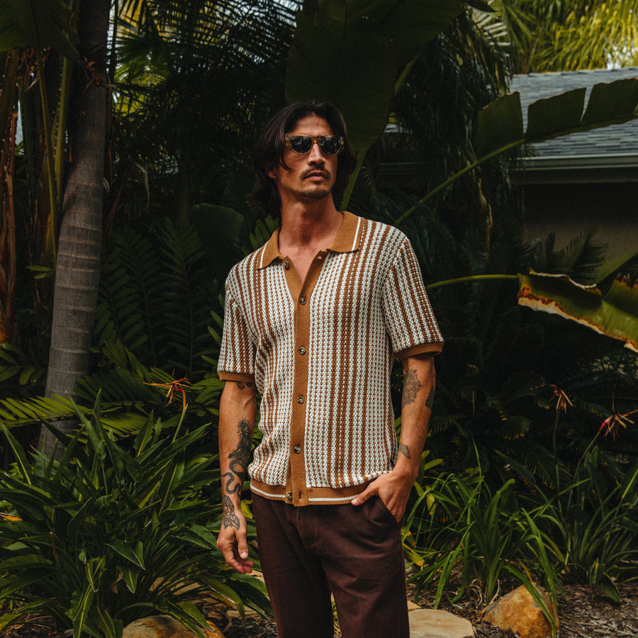 Man wearing Cabana Knit Sweater with vertical stripes in natural tones, styled for a beach-inspired casual look outdoors