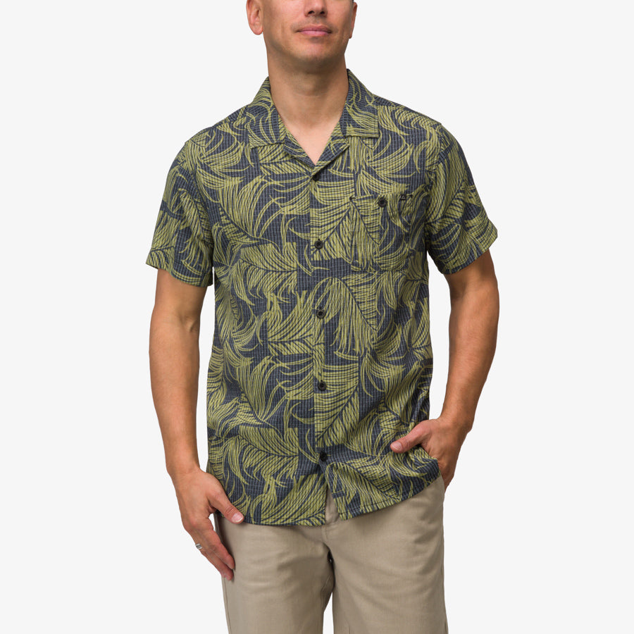 Man wearing Kantis Shirt with moss green tropical leaf pattern, front view, beach-inspired comfort apparel for men.