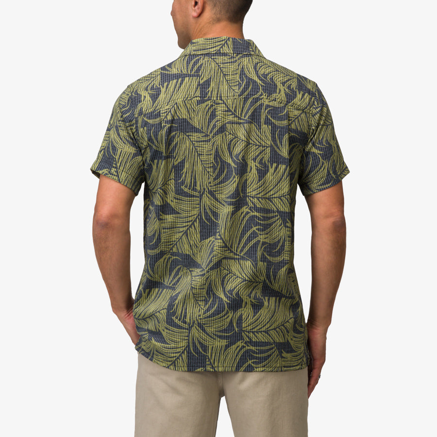 Man wearing a back view of the Kantis Shirt in moss green tropical print, surf-inspired comfort apparel for men.