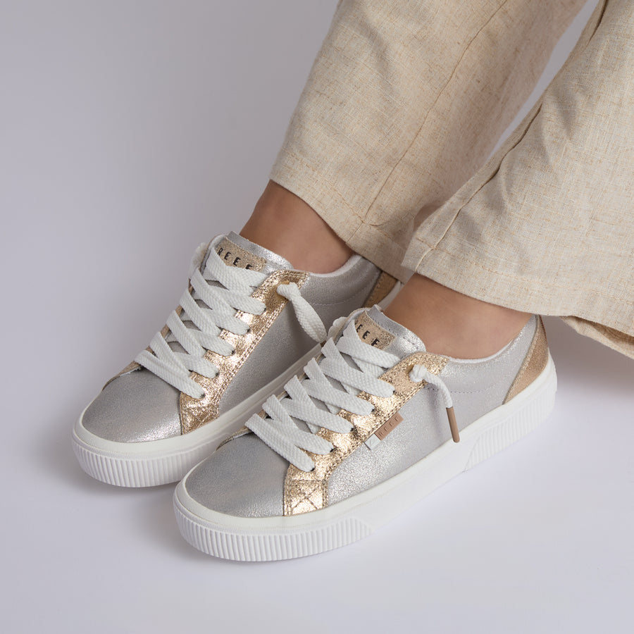 Lay Day Dawn women's sneakers facing forward, silver and gold leather with cushioned arch support, surf-inspired comfort.