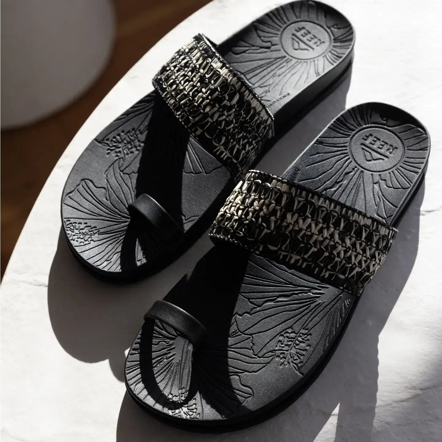 Flora Cruz sandals facing up, black with woven strap, featuring anatomical arch support and soft cushioning for all-day comfort.