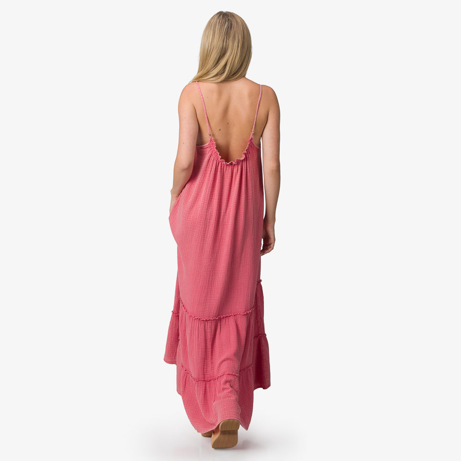 Woman wearing a mauve Lainey Maxi Dress facing away, showcasing its low back and lightweight beach-inspired fabric.