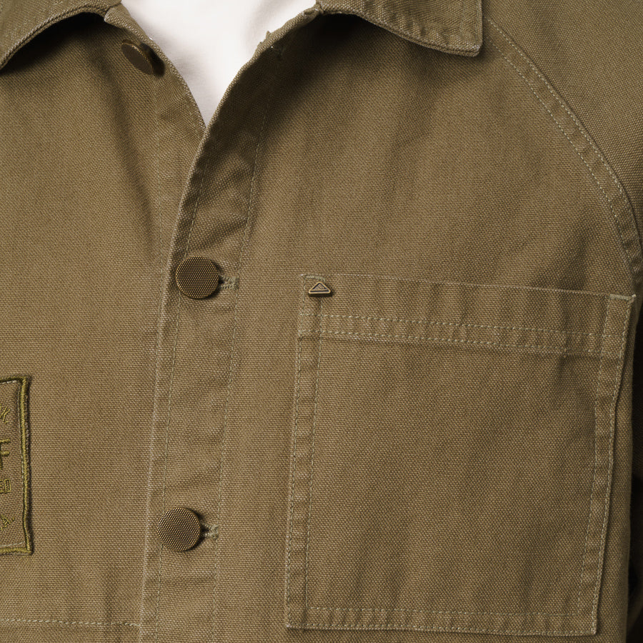 Close-up of the olive Landon Coat front chest pocket and button closure, designed for beach comfort and durability.