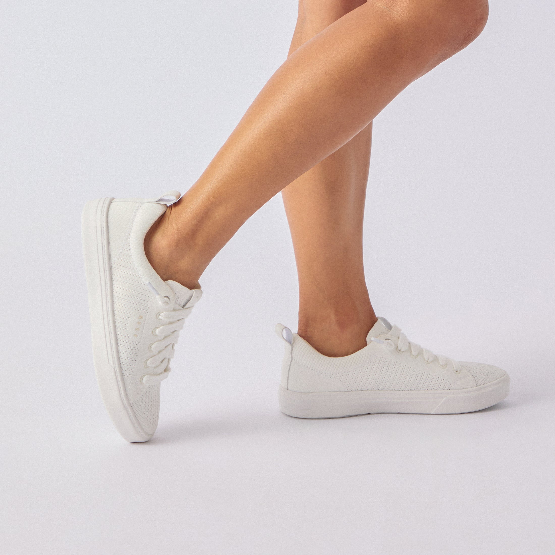 Side view of white Lay Day Lite sneaker on woman's feet, showcasing lightweight, breathable design and comfort features.