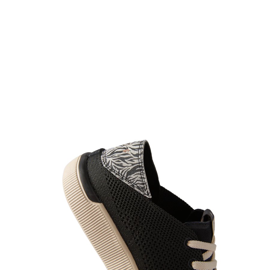 Reef Neptune women’s black sneaker facing left, showing heel with zebra print detail and lightweight sole.