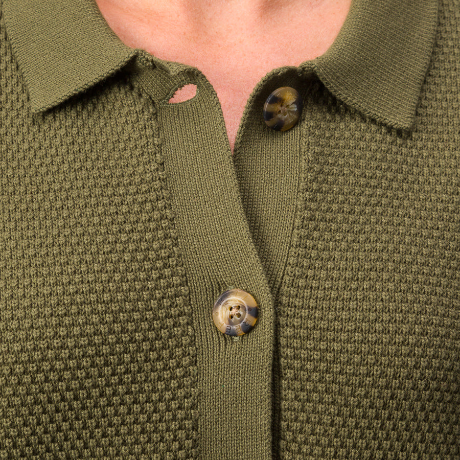 Close-up of the button and textured fabric front of the olive green Up North Sweater Top for women.