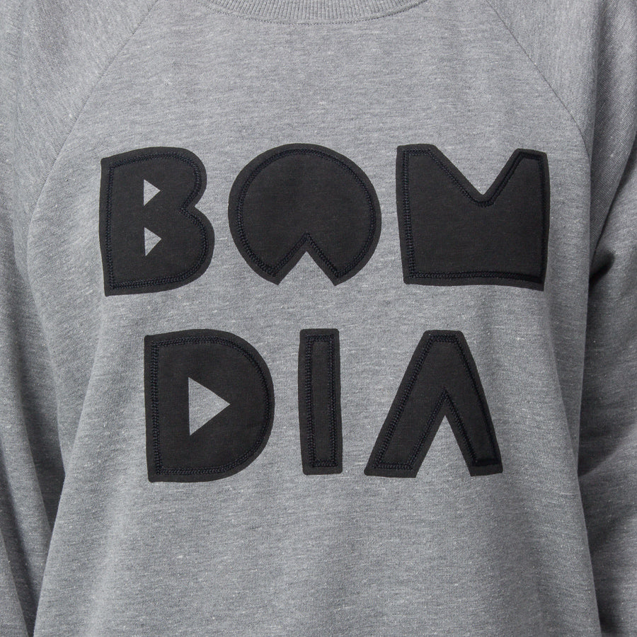 Close-up of the chest area on the women's Oversized Raglan Fleece in heather grey with bold black graphic letters.
