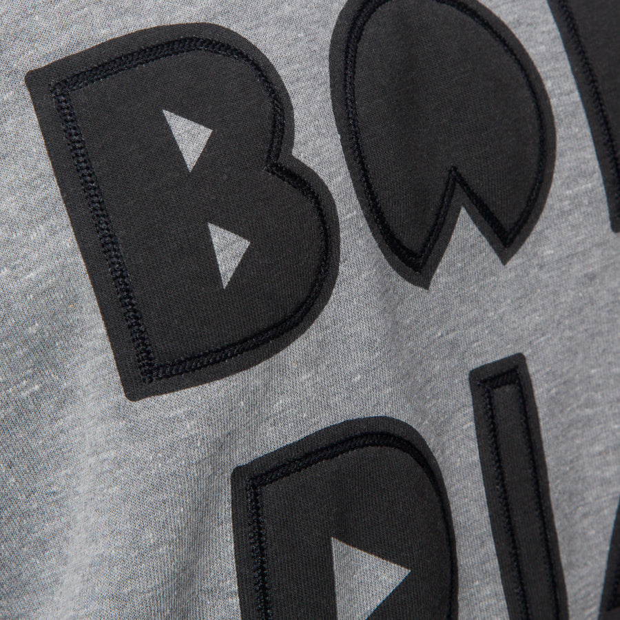 Close-up of the front chest embroidery on the Oversized Raglan Fleece in heather grey with soft, comfortable fabric.