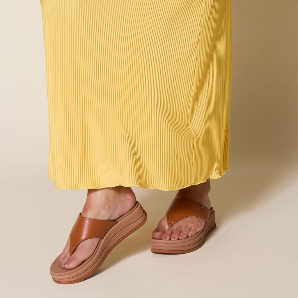 Aura Serenity sandals facing forward, close-up of brown platform sandal with cushioned arch support on woman in yellow dress