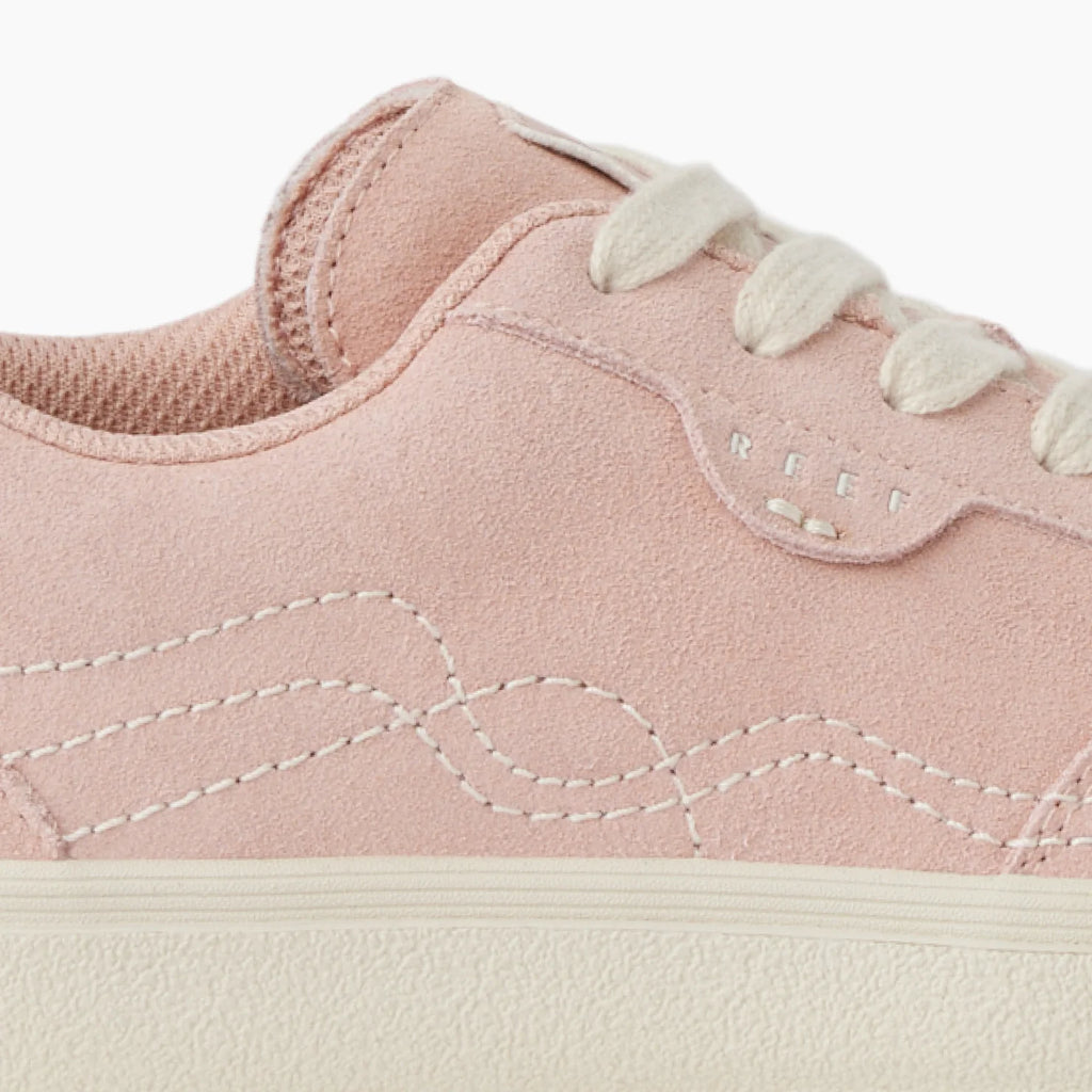 Close-up of the lateral side of the pink Boardwalk Callie sneaker showcasing soft suede, stitching, and white laces for beach comfort.