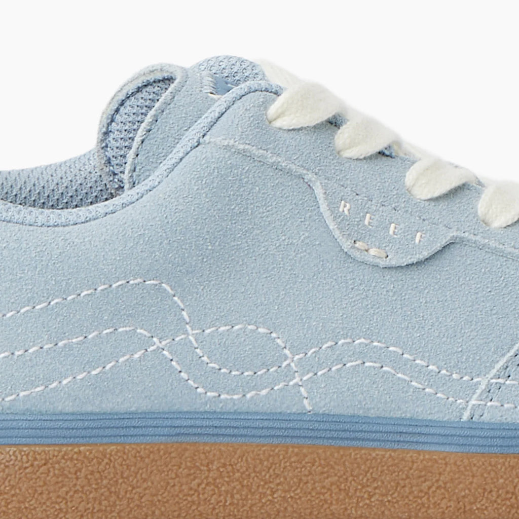 Boardwalk Callie sneaker facing left, close-up of side showing light blue suede, white laces, and rubber sole.